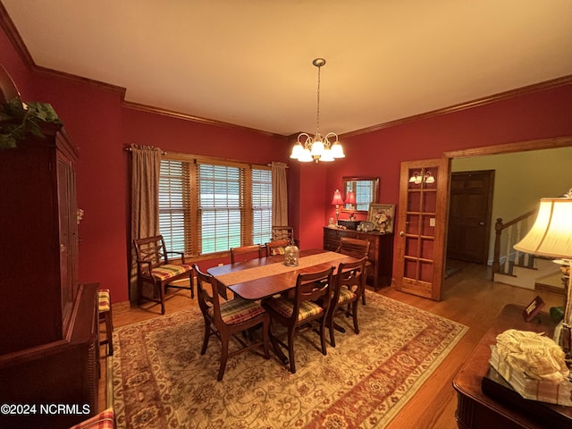 dining space featuring stairs, crown molding, wood finished floors, and an inviting chandelier