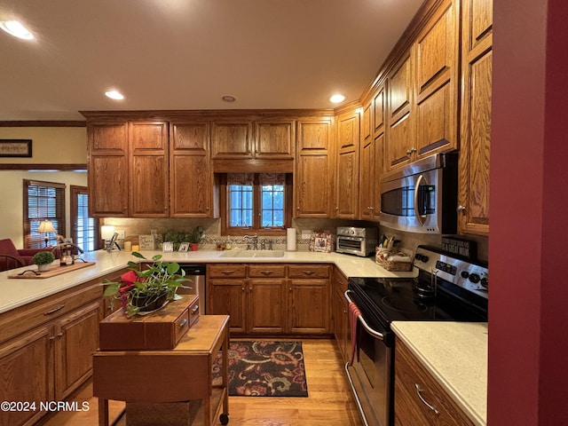 kitchen with brown cabinetry, appliances with stainless steel finishes, light wood-type flooring, wooden counters, and a sink