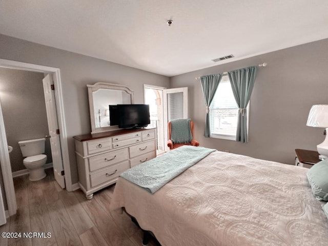 bedroom featuring connected bathroom and light hardwood / wood-style floors