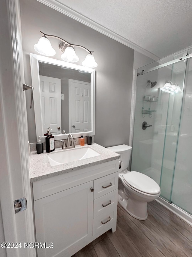 bathroom with a textured ceiling, an enclosed shower, hardwood / wood-style flooring, vanity, and toilet