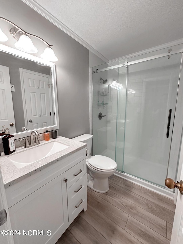 bathroom with wood-type flooring, a textured ceiling, ornamental molding, toilet, and large vanity