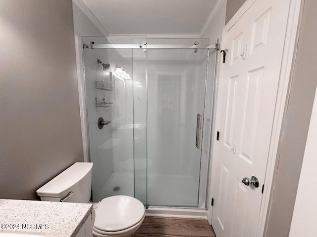 bathroom featuring toilet, crown molding, an enclosed shower, wood-type flooring, and vanity