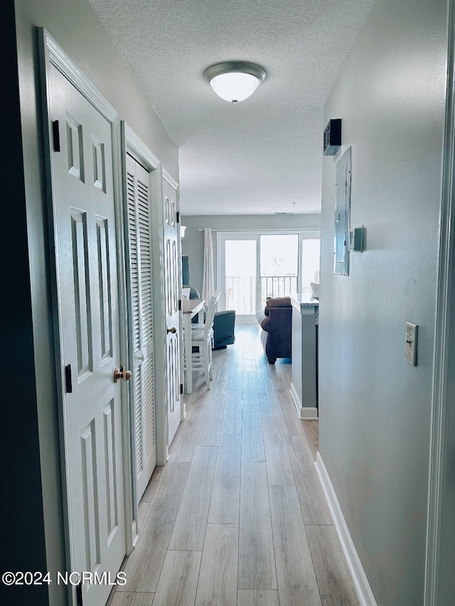 corridor featuring light hardwood / wood-style floors and a textured ceiling