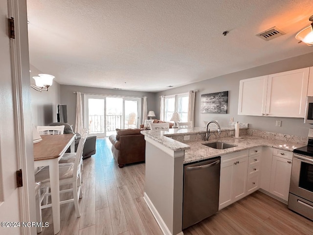 kitchen featuring light hardwood / wood-style floors, kitchen peninsula, stainless steel appliances, white cabinetry, and sink