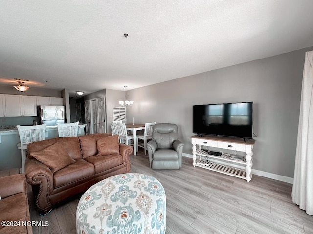 living room featuring a notable chandelier, light hardwood / wood-style floors, and a textured ceiling