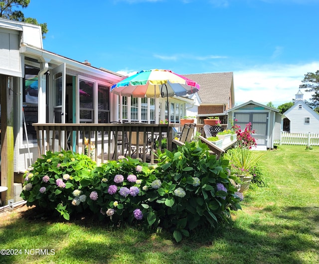 back of house featuring a wooden deck, a garage, an outdoor structure, and a lawn