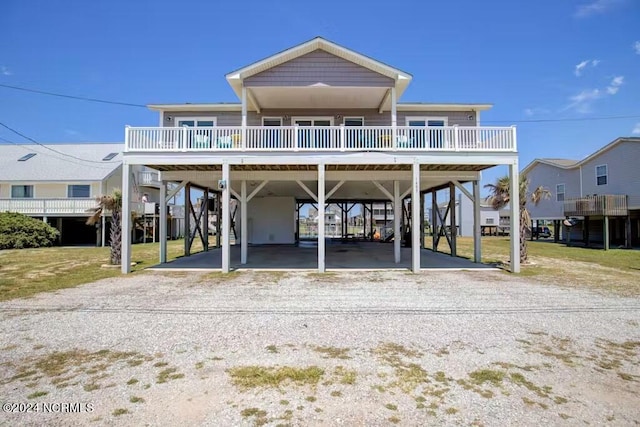 back of property featuring a carport, a balcony, and a yard