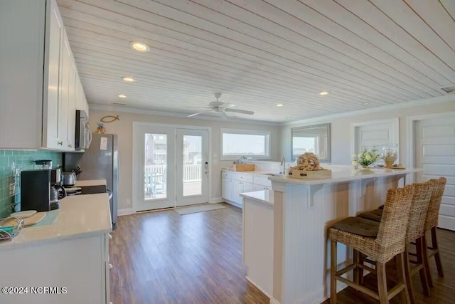 kitchen with ceiling fan, white cabinetry, ornamental molding, wood ceiling, and wood-type flooring