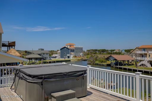 wooden deck with a hot tub and a water view