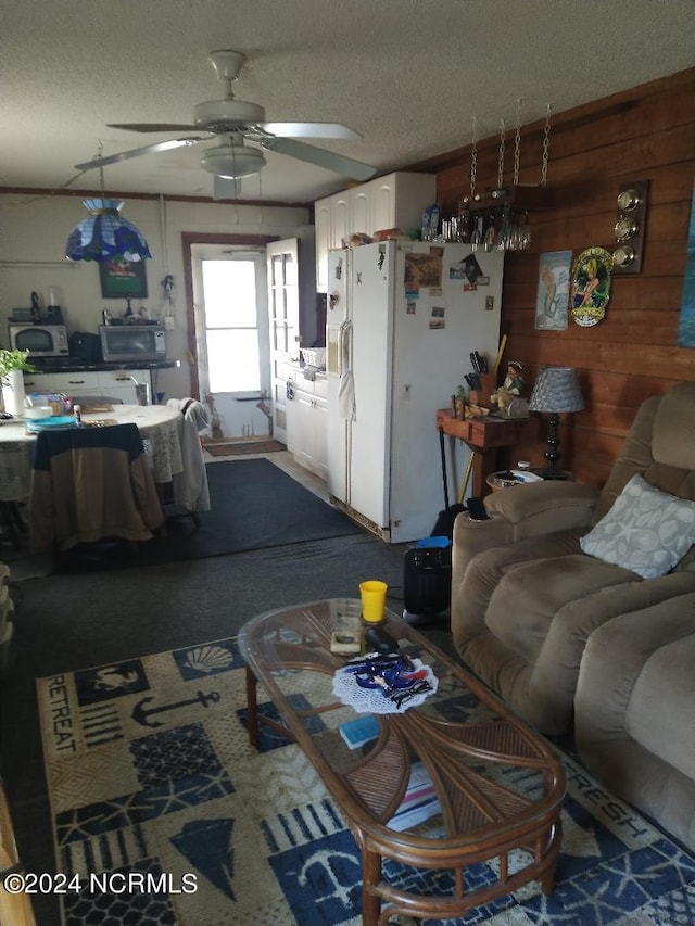 living room featuring carpet, ceiling fan, and a textured ceiling