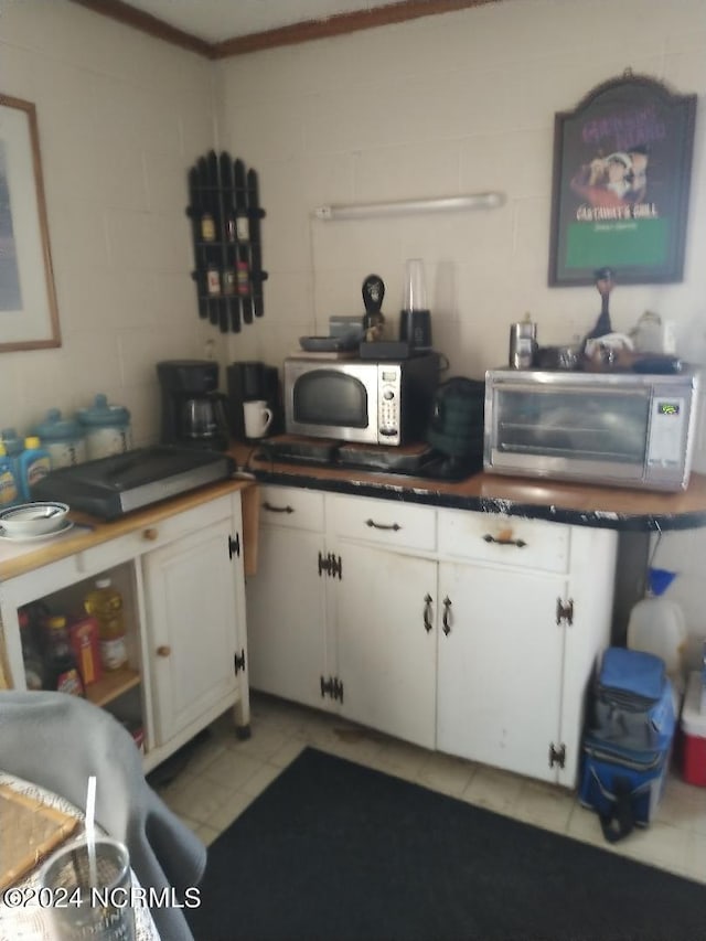 kitchen with ornamental molding, white cabinets, and light tile floors