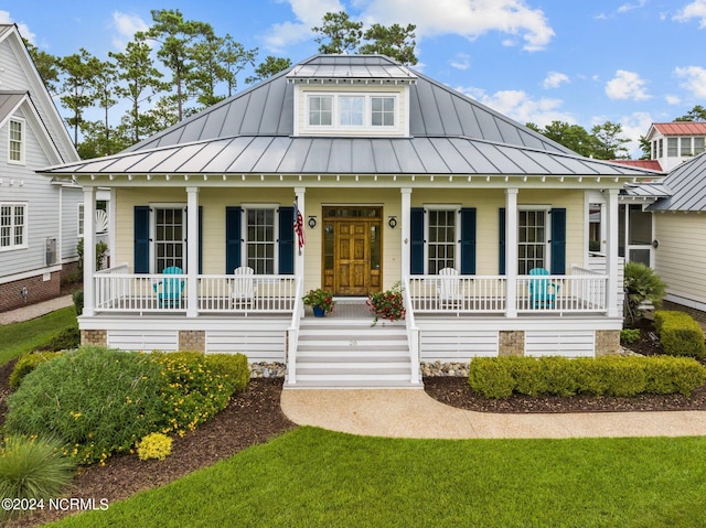 view of front of property featuring a porch, a front lawn, an outdoor structure, and a garage