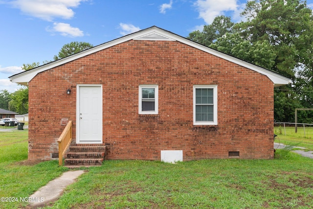 rear view of property with entry steps, a yard, brick siding, and crawl space