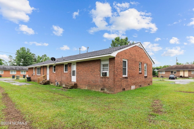 rear view of house featuring entry steps, a yard, brick siding, and crawl space