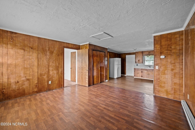 unfurnished living room with a baseboard heating unit, dark wood finished floors, and attic access