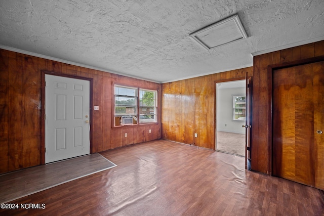 entrance foyer featuring ornamental molding, wood walls, a textured ceiling, and wood finished floors