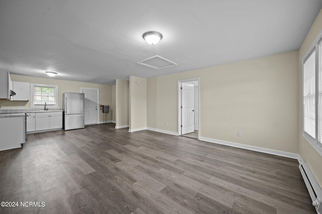 interior space with a baseboard radiator, a sink, wood finished floors, baseboards, and attic access