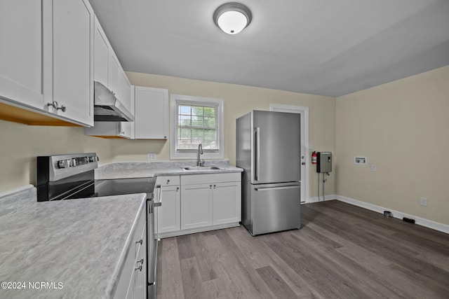 kitchen featuring under cabinet range hood, a sink, white cabinetry, light countertops, and appliances with stainless steel finishes