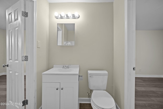 bathroom featuring toilet, wood finished floors, vanity, and baseboards