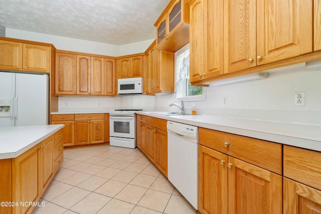 kitchen with sink, white appliances, and light tile floors