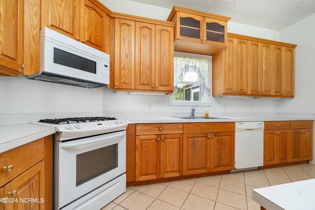 kitchen featuring white appliances, sink, and light tile floors