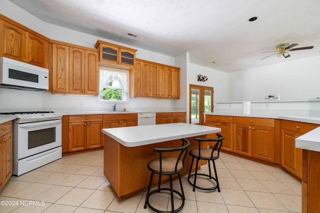 kitchen with a center island, white appliances, light tile flooring, and ceiling fan