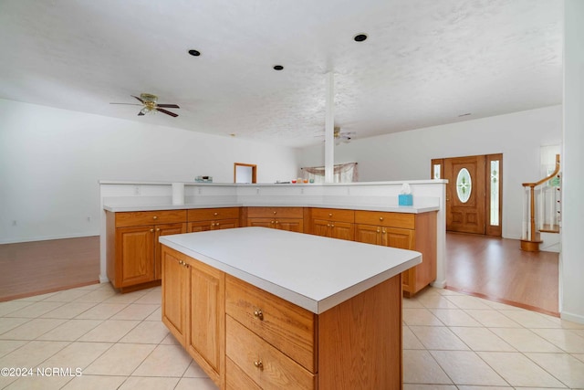 kitchen with ceiling fan, light tile flooring, and a kitchen island