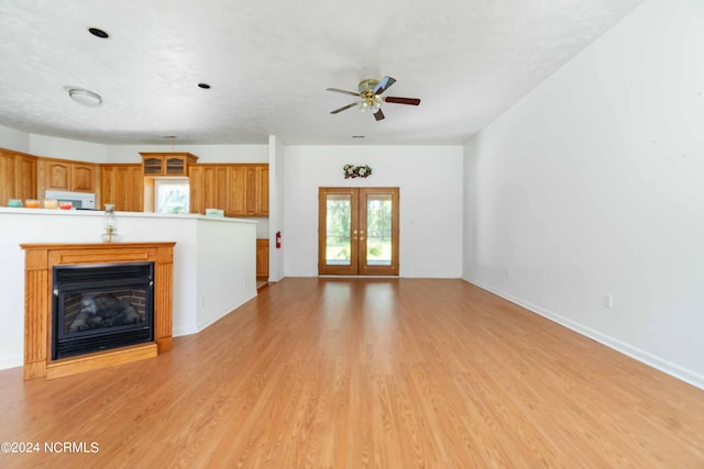 unfurnished living room featuring french doors, ceiling fan, and light hardwood / wood-style flooring