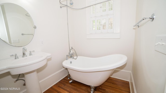 bathroom with a freestanding tub, baseboards, and wood finished floors