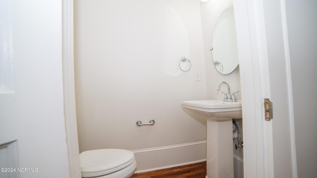 bathroom with baseboards, toilet, and wood finished floors