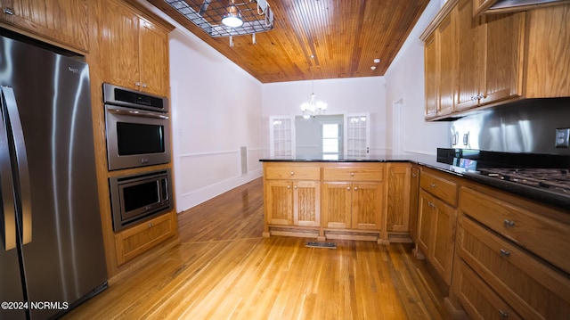 kitchen with a peninsula, appliances with stainless steel finishes, and brown cabinetry