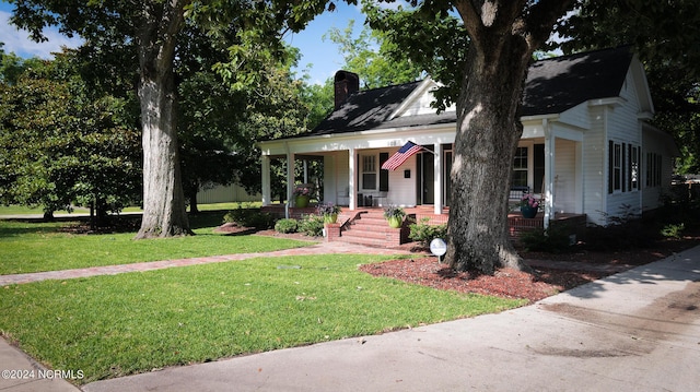 view of front facade featuring a chimney, a front lawn, and a porch