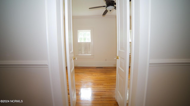 hall featuring crown molding, baseboards, and wood finished floors