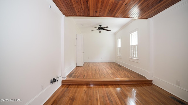 spare room with wooden ceiling, visible vents, baseboards, ornamental molding, and wood-type flooring