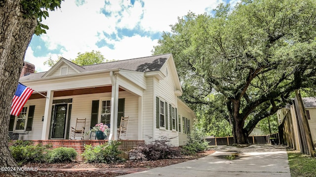 view of front of property with driveway, fence, a porch, and roof with shingles