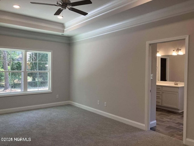 carpeted empty room with ceiling fan, ornamental molding, a tray ceiling, and sink