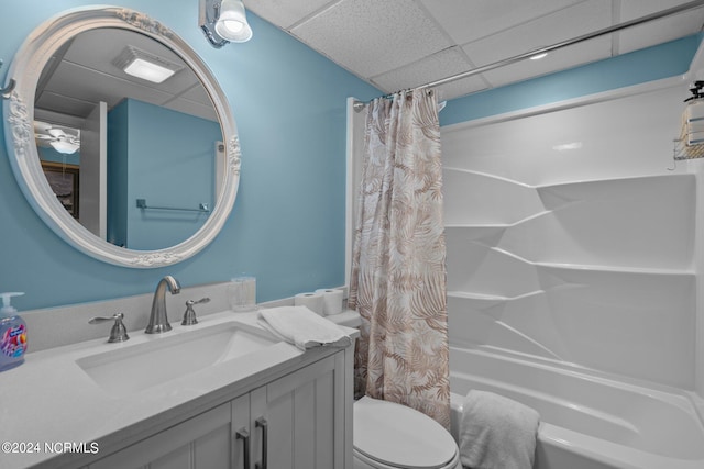 full bathroom featuring a drop ceiling, shower / bath combination with curtain, toilet, and vanity with extensive cabinet space