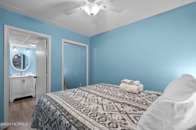 bedroom featuring a closet, dark hardwood / wood-style floors, ceiling fan, sink, and a textured ceiling