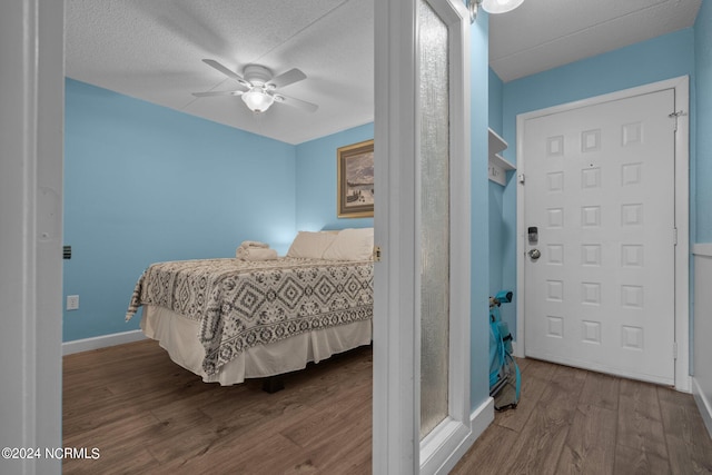 bedroom featuring dark wood-type flooring, ceiling fan, and a textured ceiling