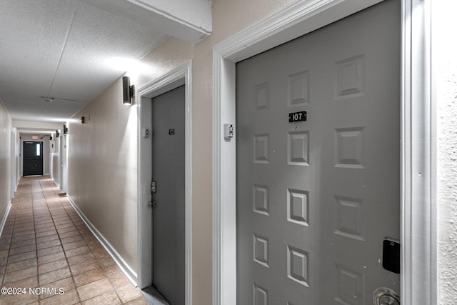 corridor with a textured ceiling and light tile flooring