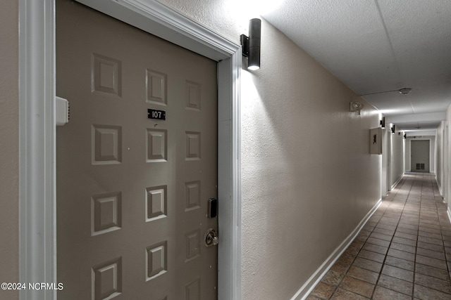 corridor featuring dark tile flooring and a textured ceiling