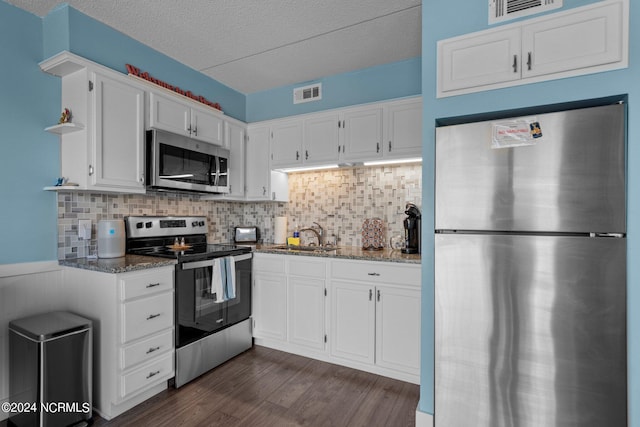 kitchen with white cabinetry, dark wood-type flooring, stainless steel appliances, stone countertops, and tasteful backsplash