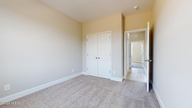 unfurnished bedroom featuring light carpet and a closet