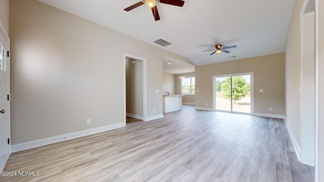 unfurnished living room with ceiling fan with notable chandelier and light hardwood / wood-style flooring