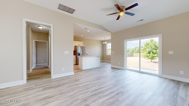 unfurnished living room with lofted ceiling, light hardwood / wood-style flooring, and ceiling fan with notable chandelier