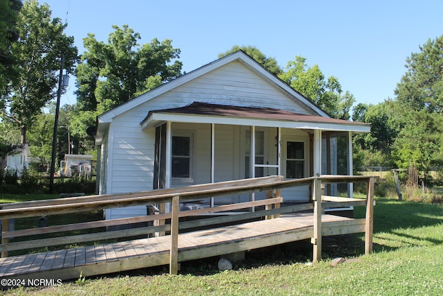 view of front facade with a wooden deck and a front lawn