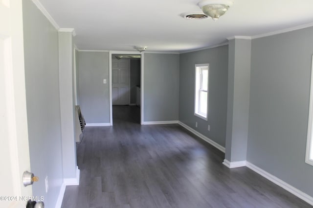 empty room with visible vents, baseboards, dark wood finished floors, and crown molding