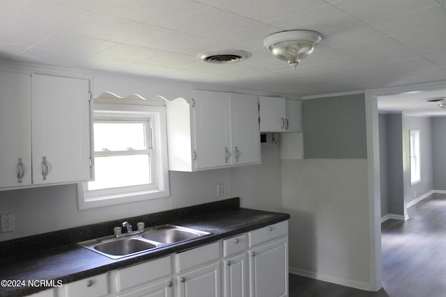 kitchen with dark countertops, white cabinets, and a sink