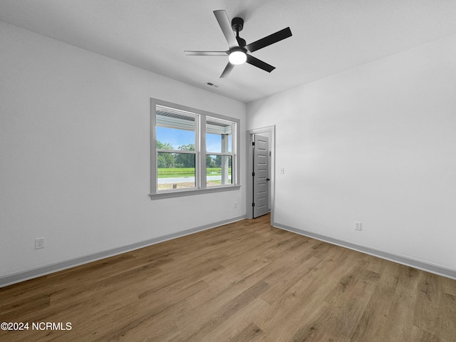 empty room with baseboards, visible vents, ceiling fan, and light wood finished floors