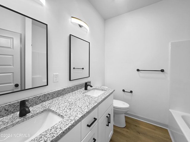 bathroom with toilet, baseboards, a sink, and wood finished floors